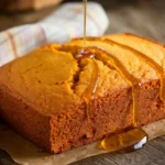 Sweet potato cornbread loaf with a drizzle of honey on a wooden table