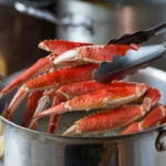 Steamed snow crab legs with steam rising from a pot.